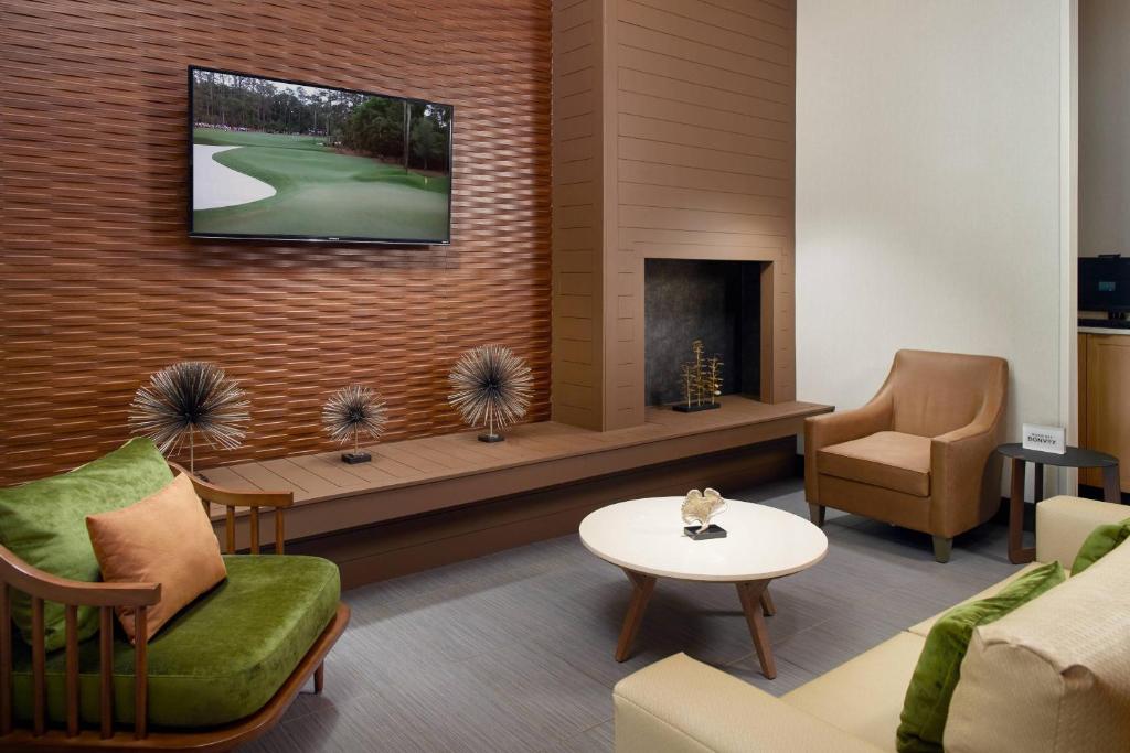 Fairfield Inn & Suites by Marriott Asheville Airport/Fletcher في فليتشر: غرفة معيشة مع تلفزيون على جدار من الطوب