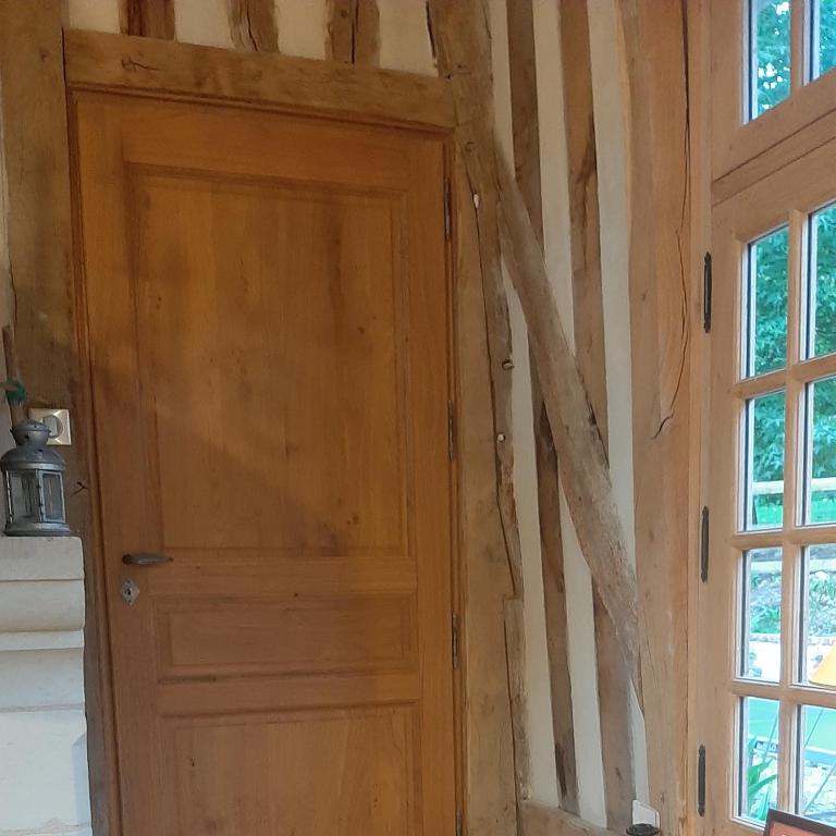 a wooden door in a room with a tree wall at Le Parc aux Oiseaux in Le Mesnil-Simon