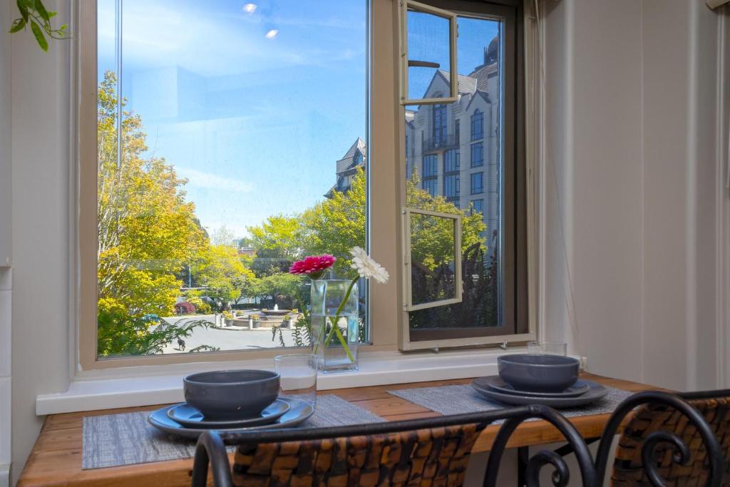 una mesa con dos platos y un jarrón con flores en una ventana en Deluxe 2 Bed, 2 Bath, 5 Min Walk To Downtown And Seawalk, en Victoria