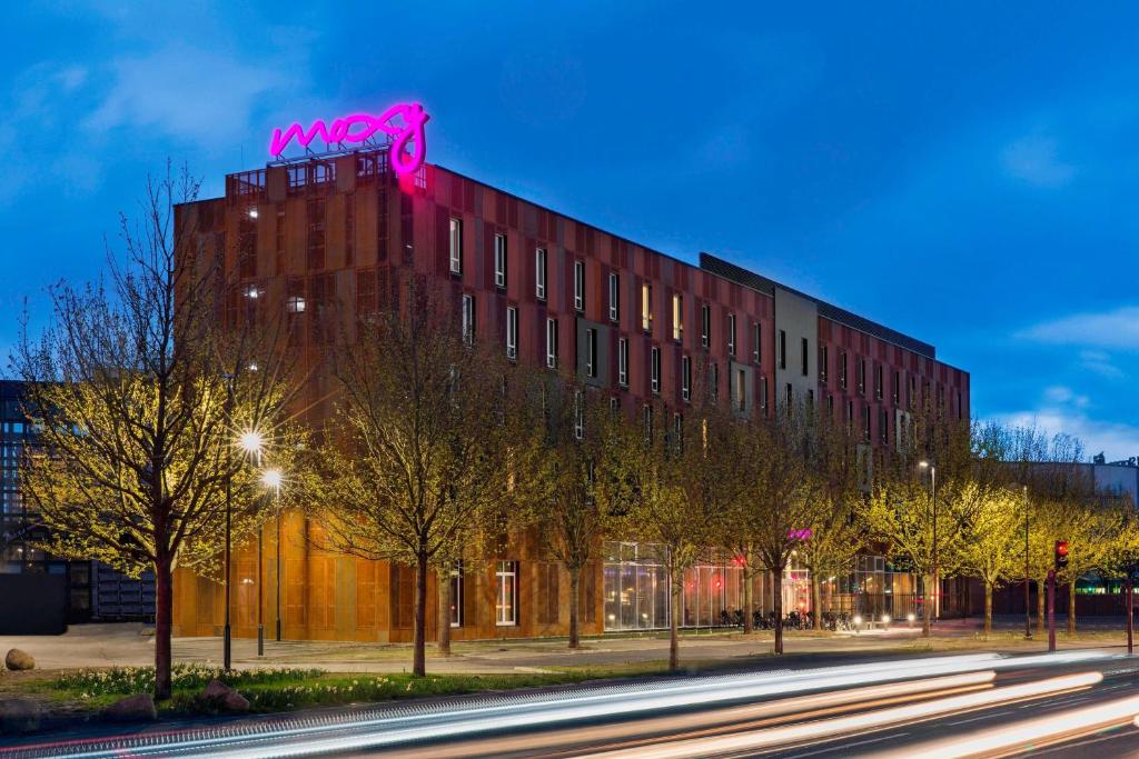 ein Gebäude mit einem rosa Schild darüber in der Unterkunft Moxy Copenhagen Sydhavnen in Kopenhagen