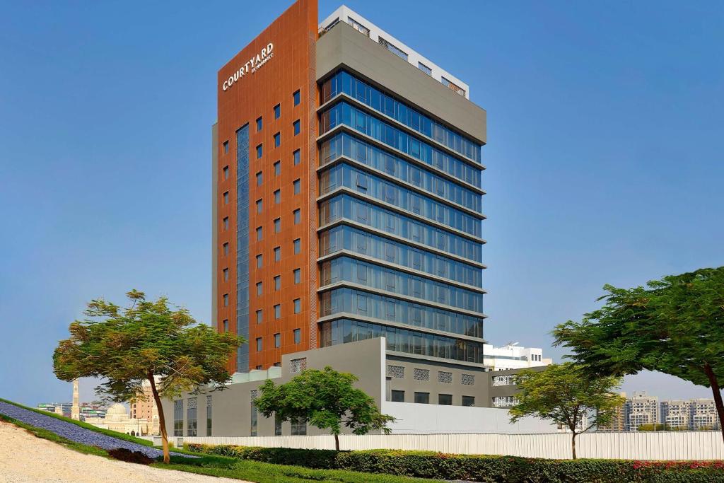 a tall red building with trees in front of it at Courtyard by Marriott Culture Village, Dubai in Dubai