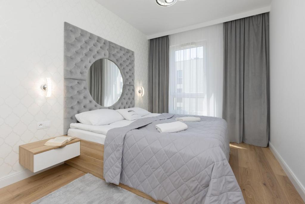 een witte slaapkamer met een groot bed en een spiegel bij Praga Arte Apartments with Parking & Balcony by Renters in Warschau