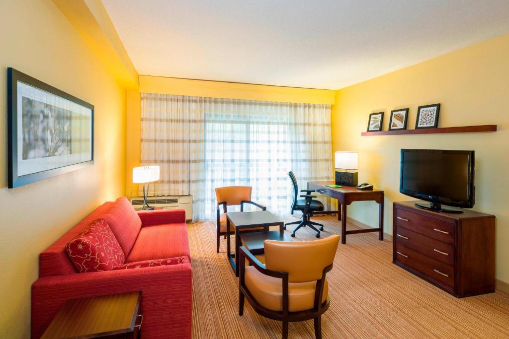 a living room with a red couch and a television at Courtyard Wilmington Brandywine in Wilmington