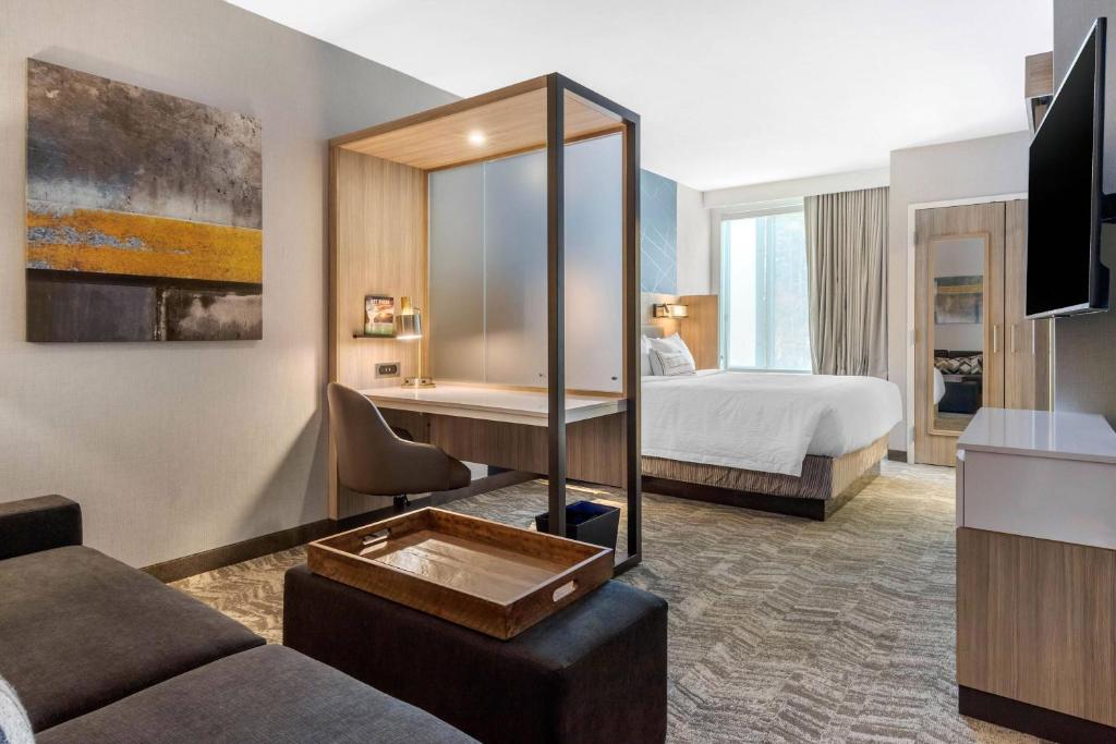 シャーロットにあるSpringHill Suites Charlotte Southwestのベッドとデスクが備わるホテルルームです。