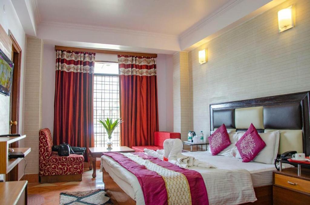 Cette chambre comprend un grand lit avec des rideaux rouges. dans l'établissement The Abhinandan, à Mussoorie
