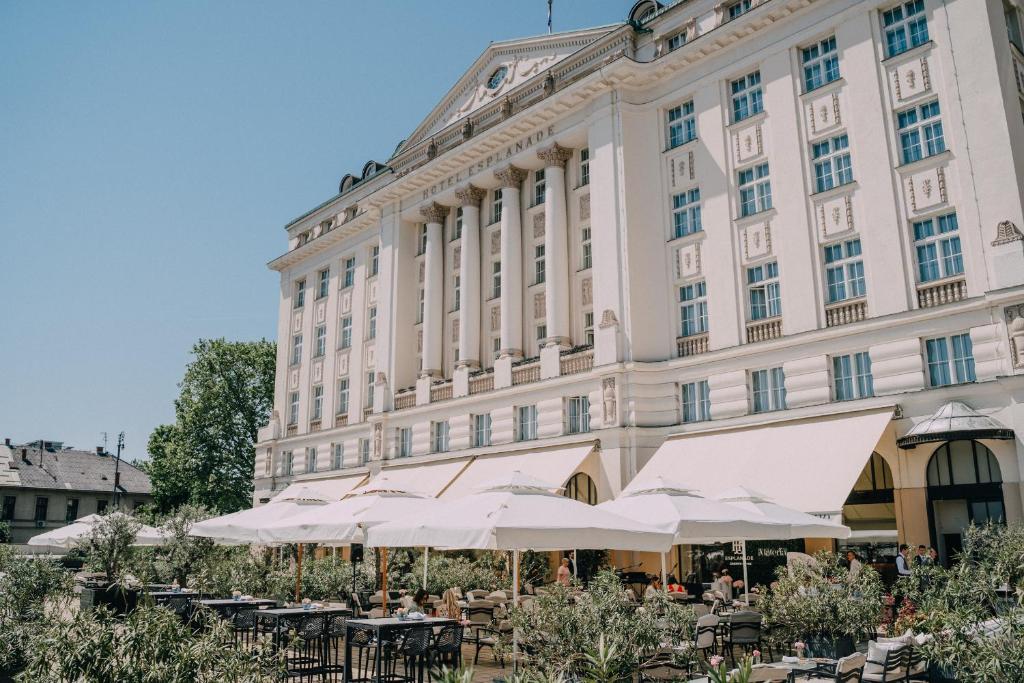 a building with tables and umbrellas in front of it at Esplanade Zagreb Hotel in Zagreb