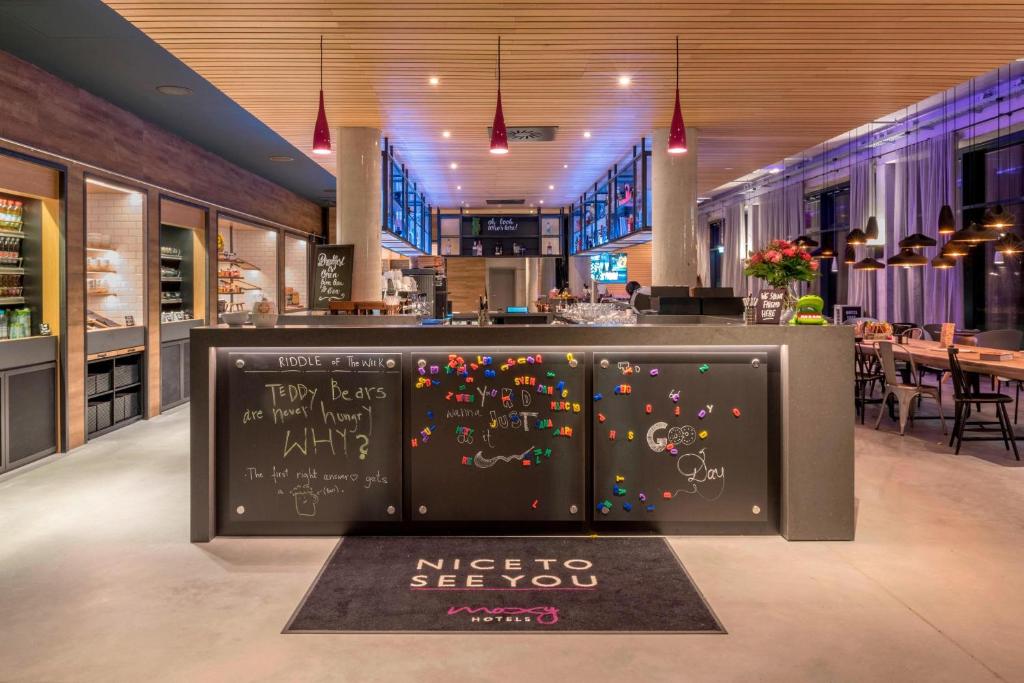 a restaurant with a bar with writing on it at Moxy Munich Messe in Aschheim