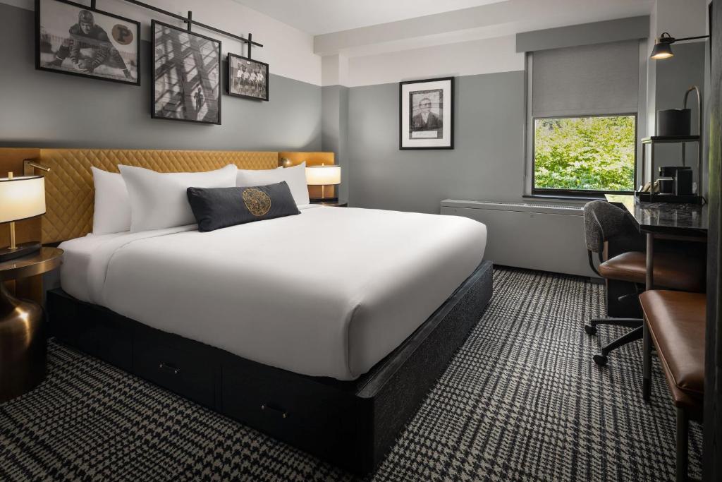 a bedroom with a bed and a desk and a chair at The Union Club Hotel at Purdue University, Autograph Collection in West Lafayette