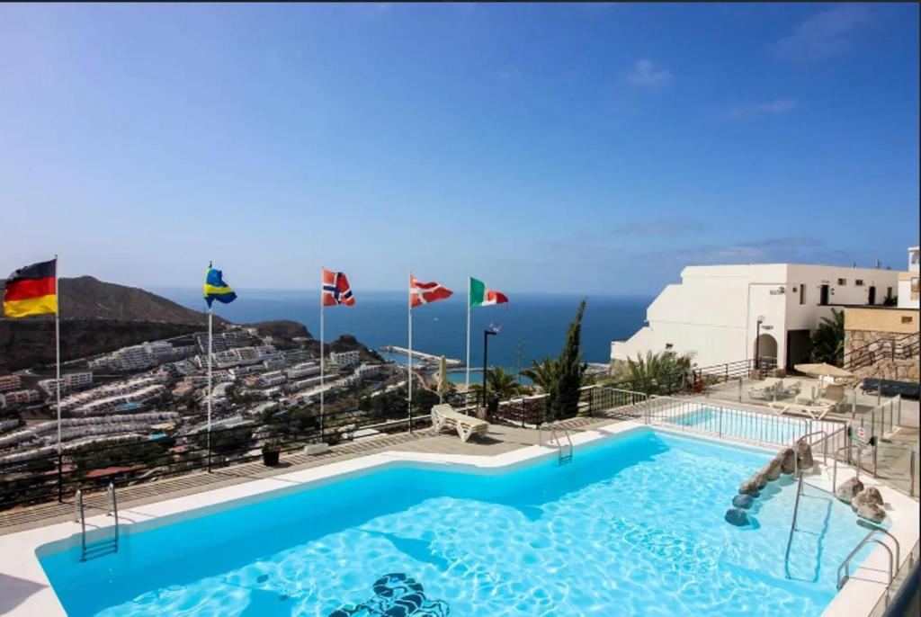 a pool on top of a building with the ocean in the background at Ca Cristina "Scorpio" Puerto Rico in Puerto Rico de Gran Canaria