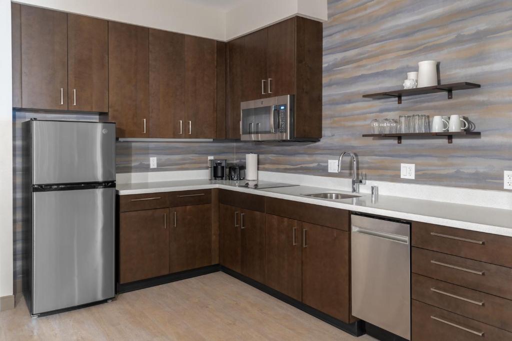 a kitchen with wooden cabinets and a stainless steel refrigerator at Residence Inn by Marriott Lancaster Palmdale in Lancaster