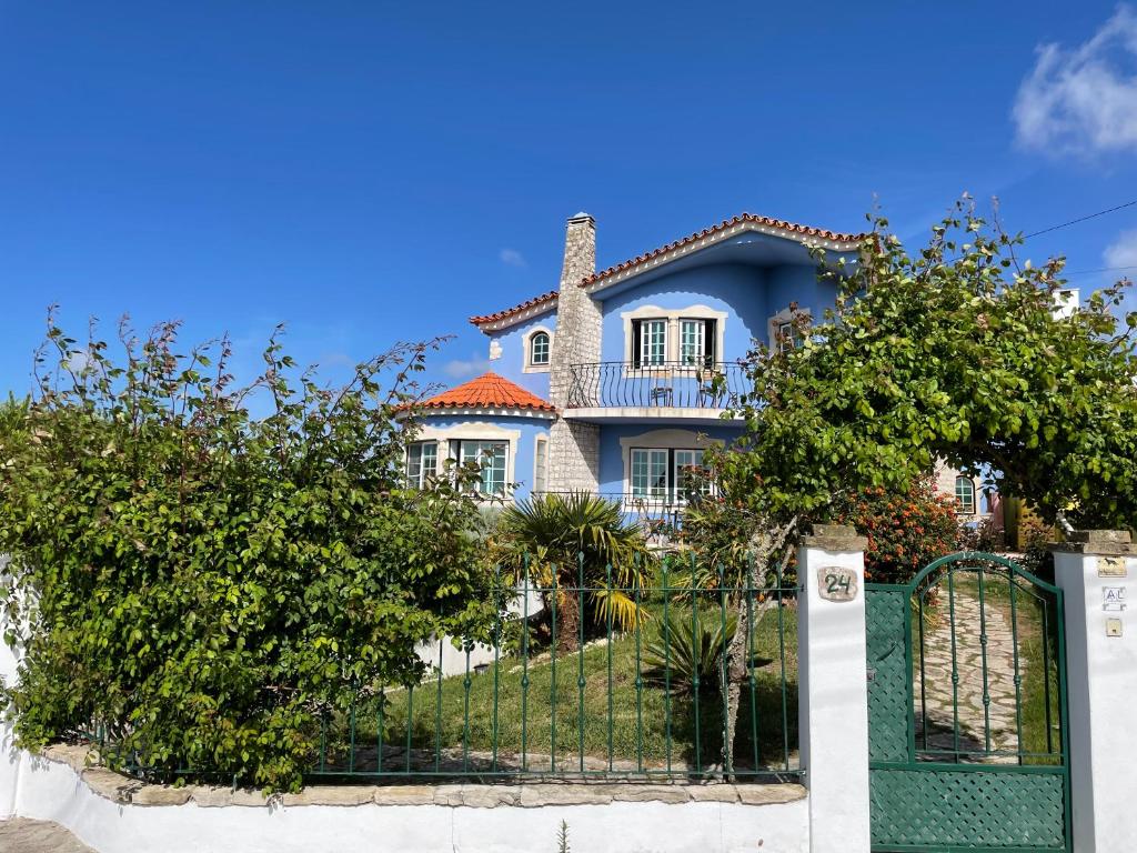 a blue house with a gate and trees at NO CEU - A fully private flat in the sky with Ocean view in Atouguia da Baleia