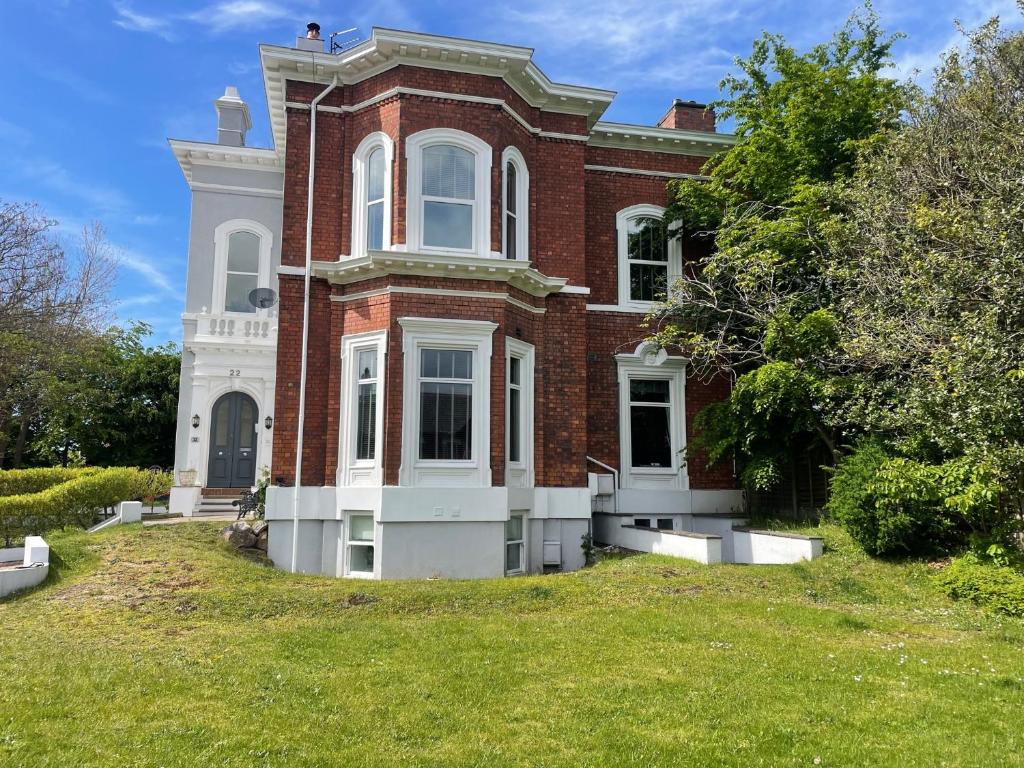 a large red brick house with a grass yard at Beach House 3 Bed Penthouse Apartment in Southport