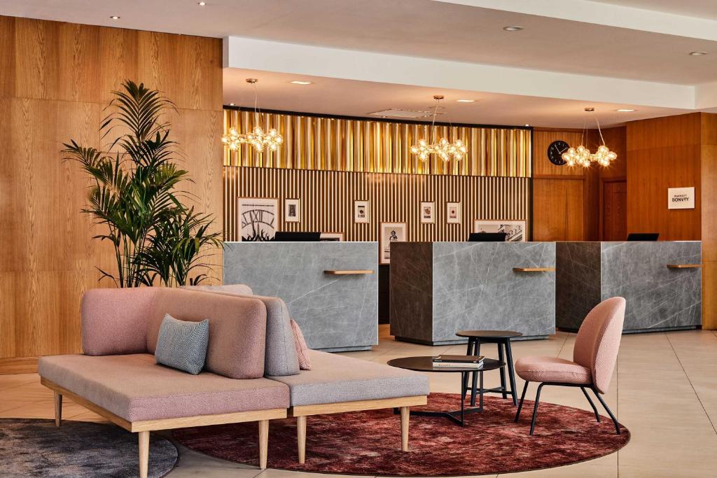 a lobby with a couch and chairs and a counter at Sheraton Poznan Hotel in Poznań