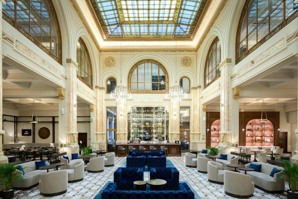 a lobby with blue tables and chairs in a building at The Marmorosch Bucharest, Autograph Collection in Bucharest