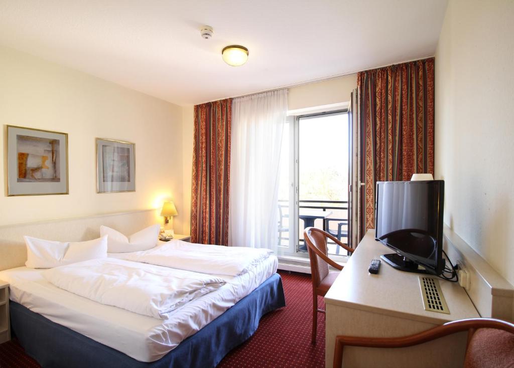 um quarto de hotel com uma cama e uma secretária com um computador em Morada Hotel Gothaer Hof em Gotha