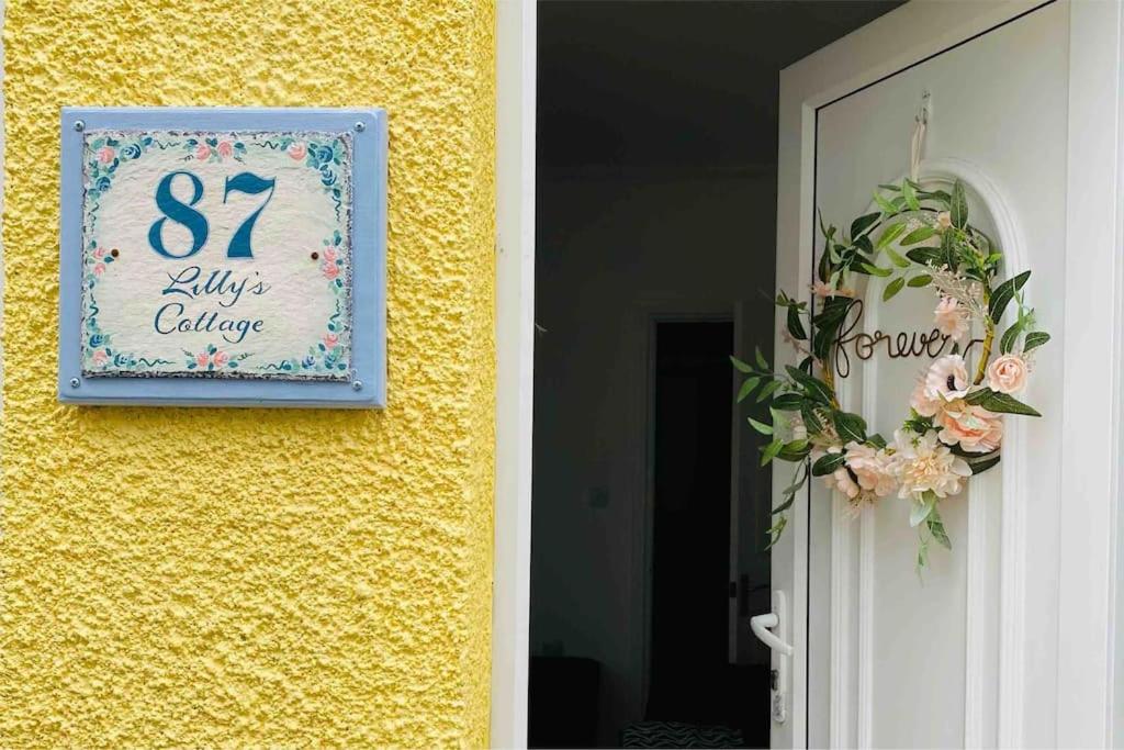 un panneau sur le côté d'une paroi jaune à côté d'une porte dans l'établissement Lilly’s Cottage, Filey, Sleeps 8, à Filey