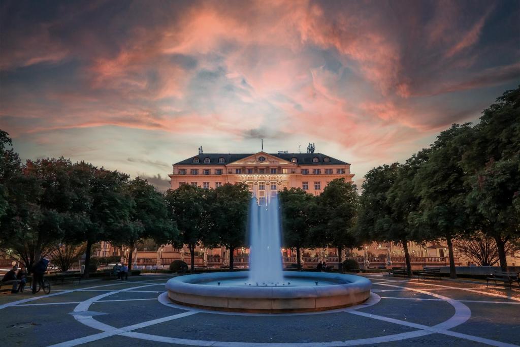 a fountain in front of a building with a sunset at Esplanade Zagreb Hotel in Zagreb