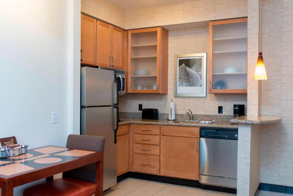 cocina con armarios de madera y nevera de acero inoxidable en Residence Inn Moline Quad Cities, en Moline