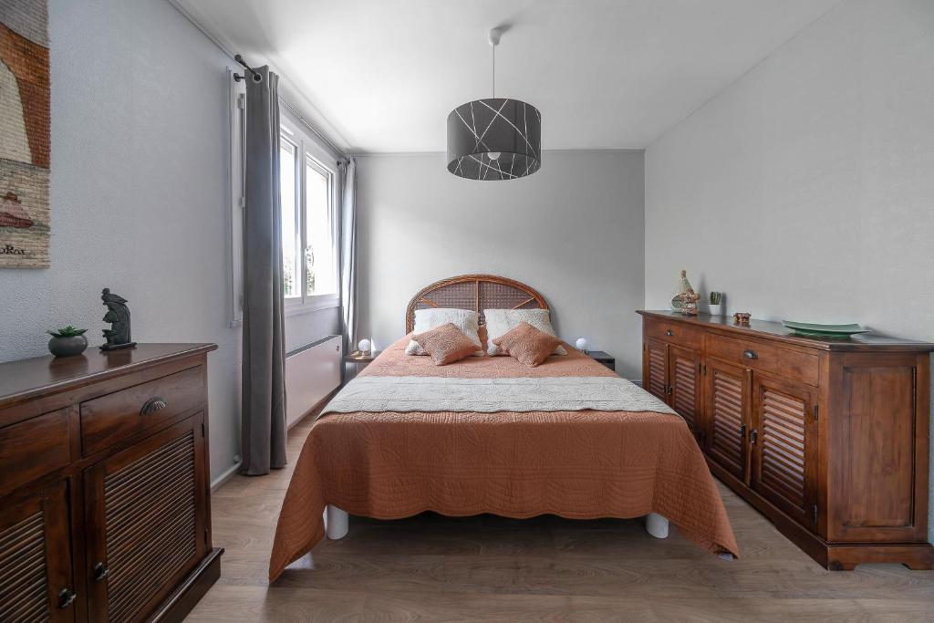 een slaapkamer met een bed en een houten dressoir bij Le Raymond - Appartement proche du centre sportif, des rives de l'Allier et du centre-ville - parking in Vichy