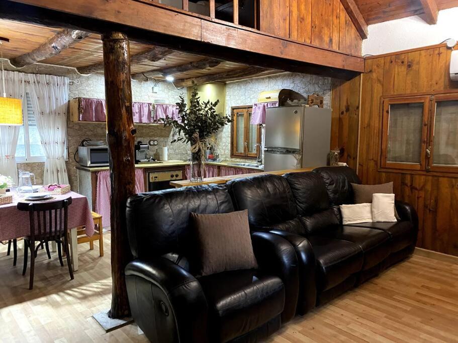 sala de estar con sofá de cuero negro en la cocina en Casita rural con piscina en La Torre de Claramunt