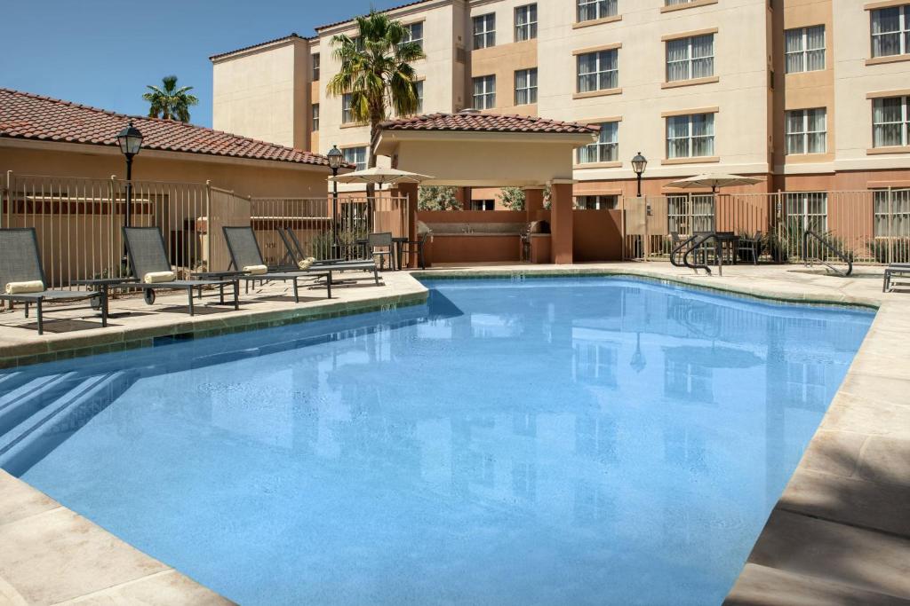 a swimming pool with chairs and a building at Residence Inn by Marriott Phoenix Airport in Phoenix