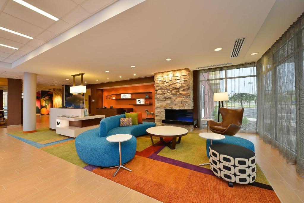 a lobby with blue chairs and tables in a hotel at Fairfield Inn & Suites by Marriott Elmira Corning in Horseheads