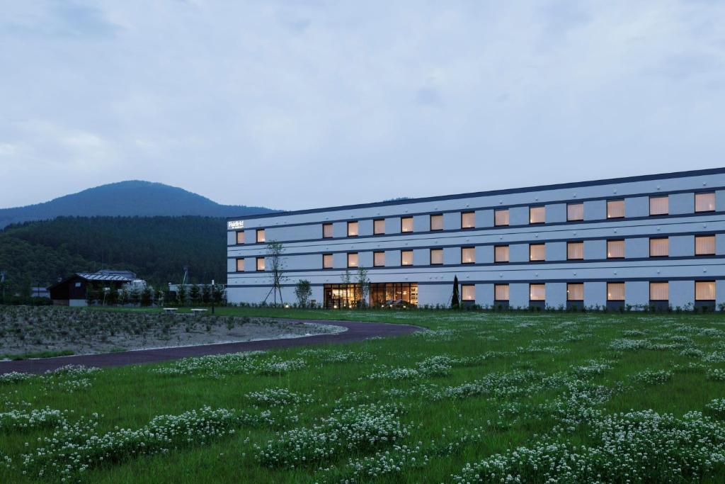 un edificio con un campo de césped delante de él en Fairfield by Marriott Hokkaido Minamifurano, en Minamifurano