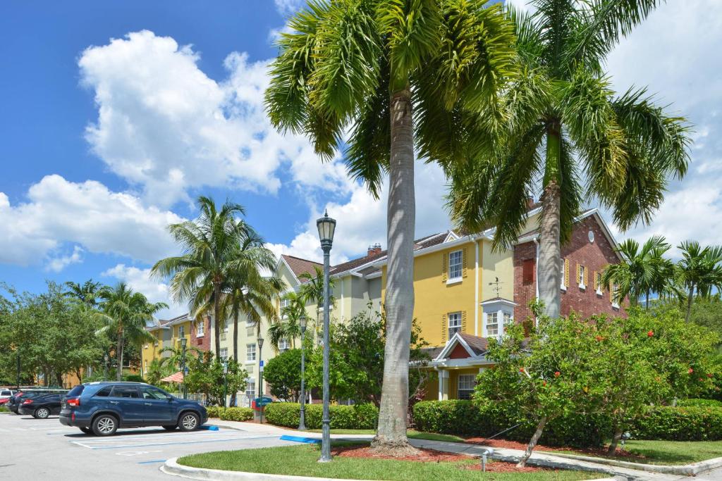 uma rua com palmeiras e um edifício amarelo em TownePlace Suites Miami Lakes em Miami Lakes