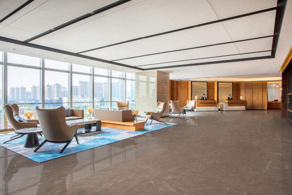 un vestíbulo de oficina con sillas, mesas y ventanas en Fairfield by Marriott Foshan Nanhai, en Foshan