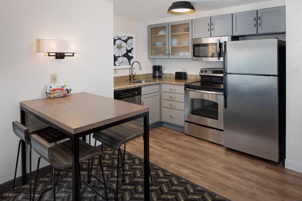 cocina con electrodomésticos de acero inoxidable y mesa de madera en Residence Inn Boston Dedham en Dedham