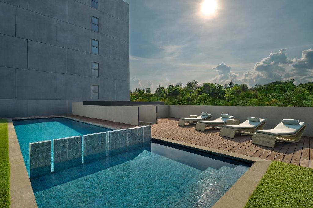 a swimming pool with lounge chairs next to a building at Four Points by Sheraton Balikpapan in Balikpapan