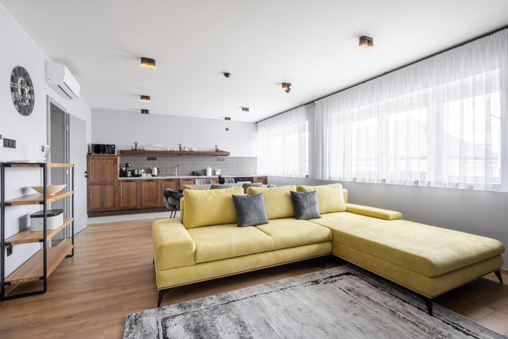 ein Wohnzimmer mit einem gelben Sofa und einer Küche in der Unterkunft Radnoti Home in Veszprém