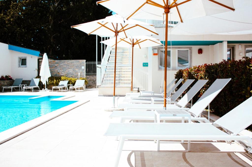 a row of white chairs and umbrellas next to a swimming pool at Principe Alogna Hotel & SPA in Altavilla Milicia