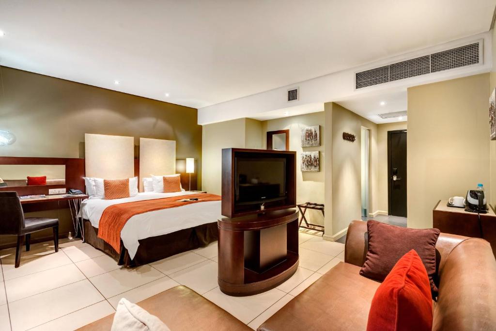 a hotel room with a bed and a desk at Protea Hotel by Marriott Transit O.R. Tambo Airport in Kempton Park