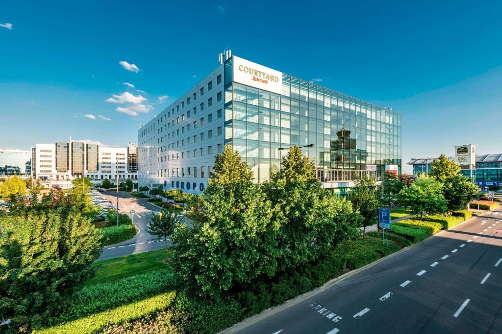a tall glass building with a road in front of it at Courtyard by Marriott Prague Airport in Prague