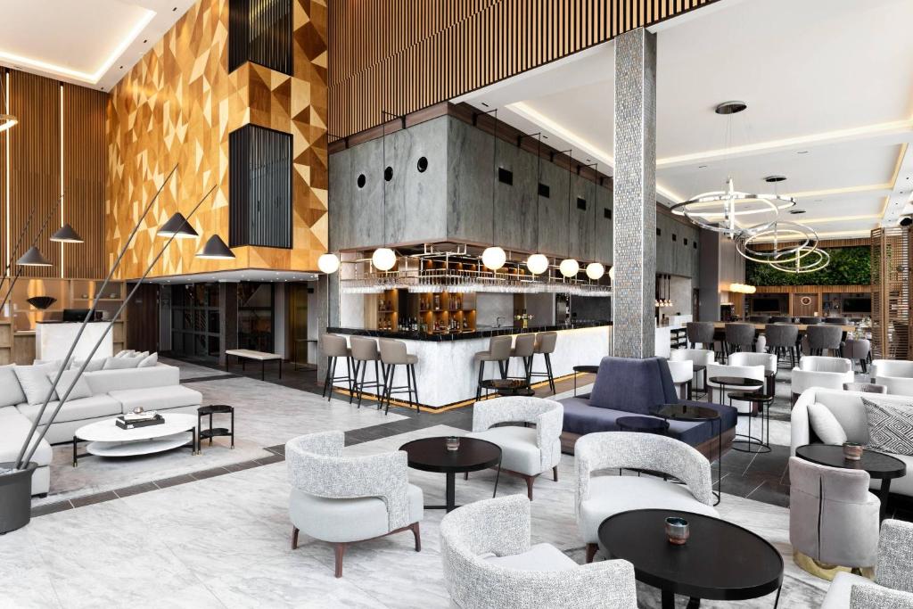 a lobby with tables and chairs and a bar at AC Hotel by Marriott Stockholm Ulriksdal in Solna