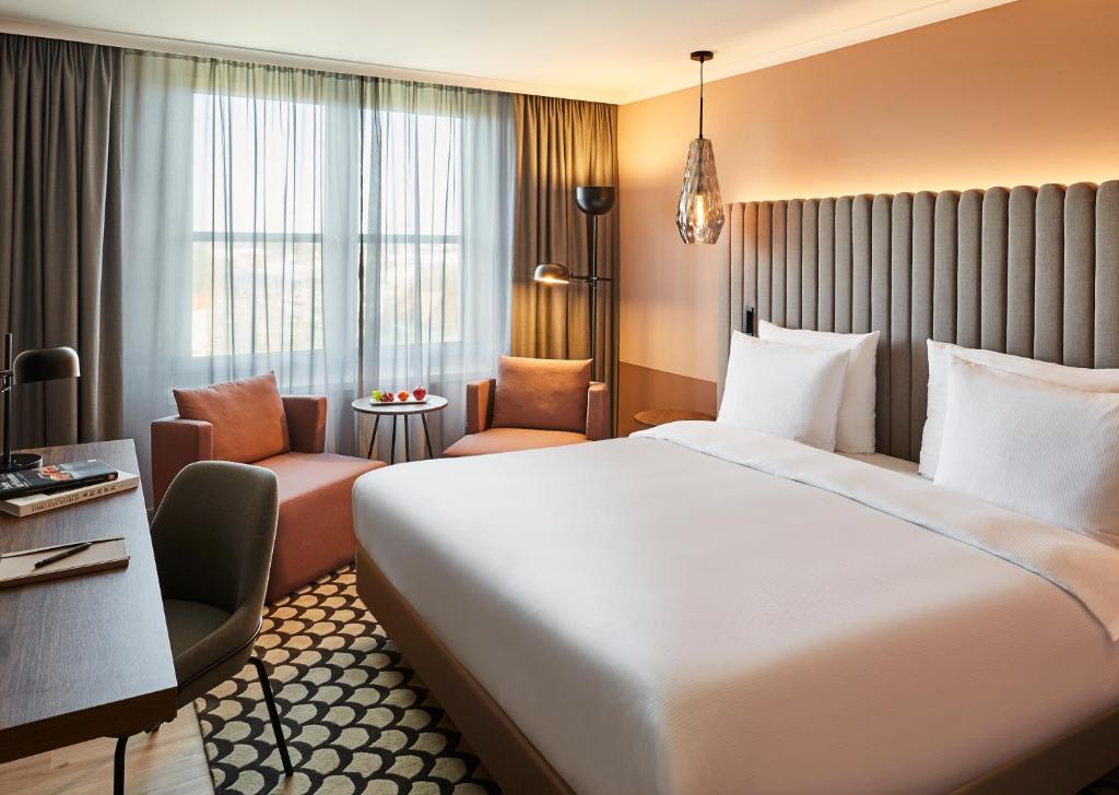 シュトゥットガルトにあるプルマン シュトゥットガルト フォンタナの大きなベッドと椅子が備わるホテルルームです。