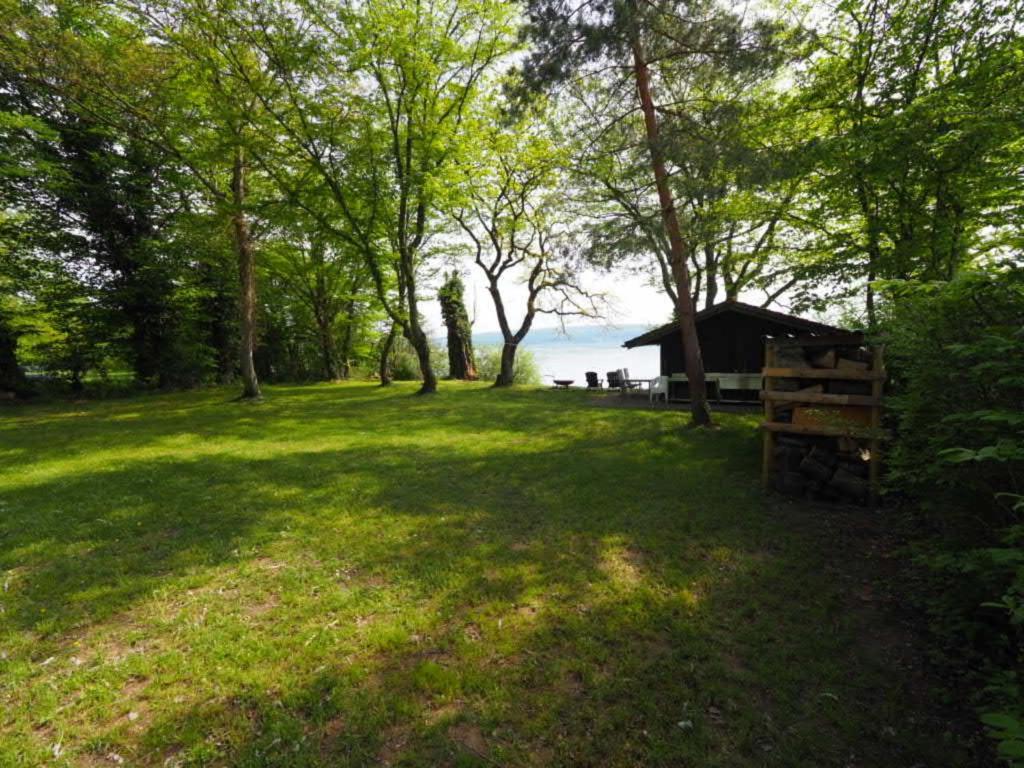 un campo de césped con cenador y árboles en Häuschen direkt am See, en Reichenau