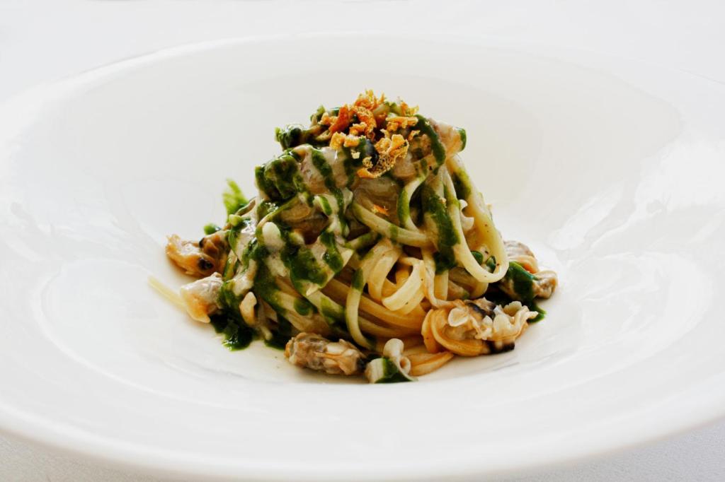 a white plate with pasta and vegetables on it at Principe Alogna Hotel & SPA in Altavilla Milicia