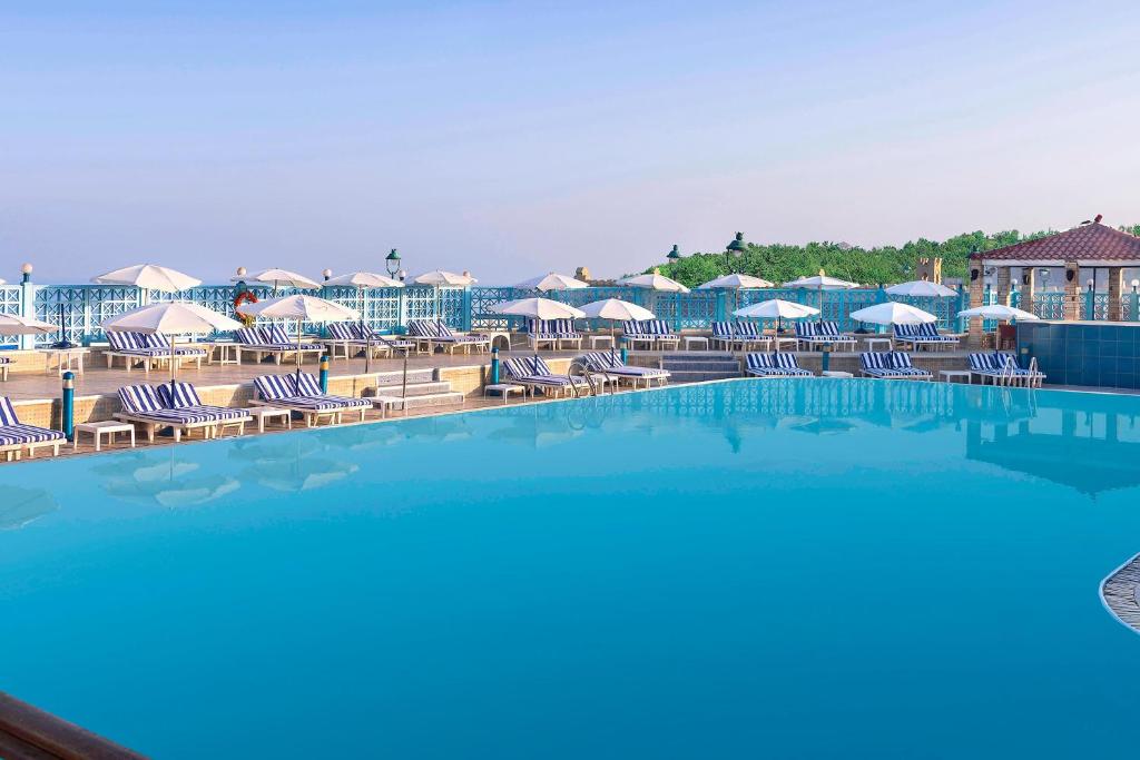 a swimming pool with chairs and umbrellas at a resort at Sheraton Montazah Hotel in Alexandria