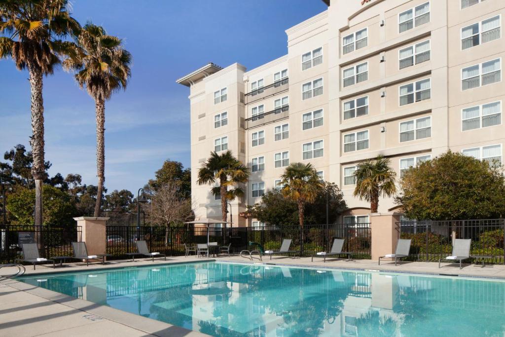 a swimming pool in front of a building with palm trees at Residence Inn by Marriott Newark Silicon Valley in Newark