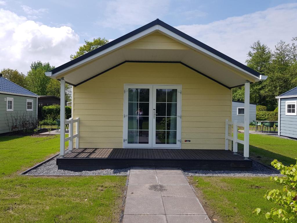 een klein geel huis met een veranda bij De Bijsselse Enk, Noors chalet 14 in Nunspeet