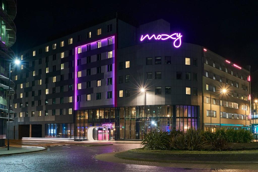 un edificio mozageno con un'insegna al neon viola di Moxy Southampton a Southampton