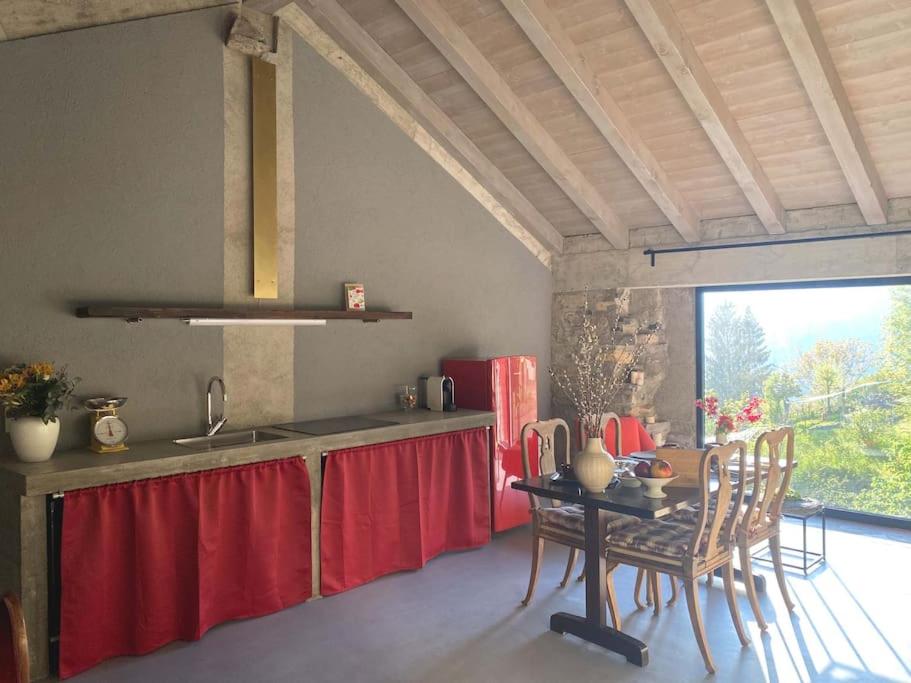 une cuisine avec une table et un rideau rouge dans l'établissement Casa 1000fiori, à Faggeto Lario 