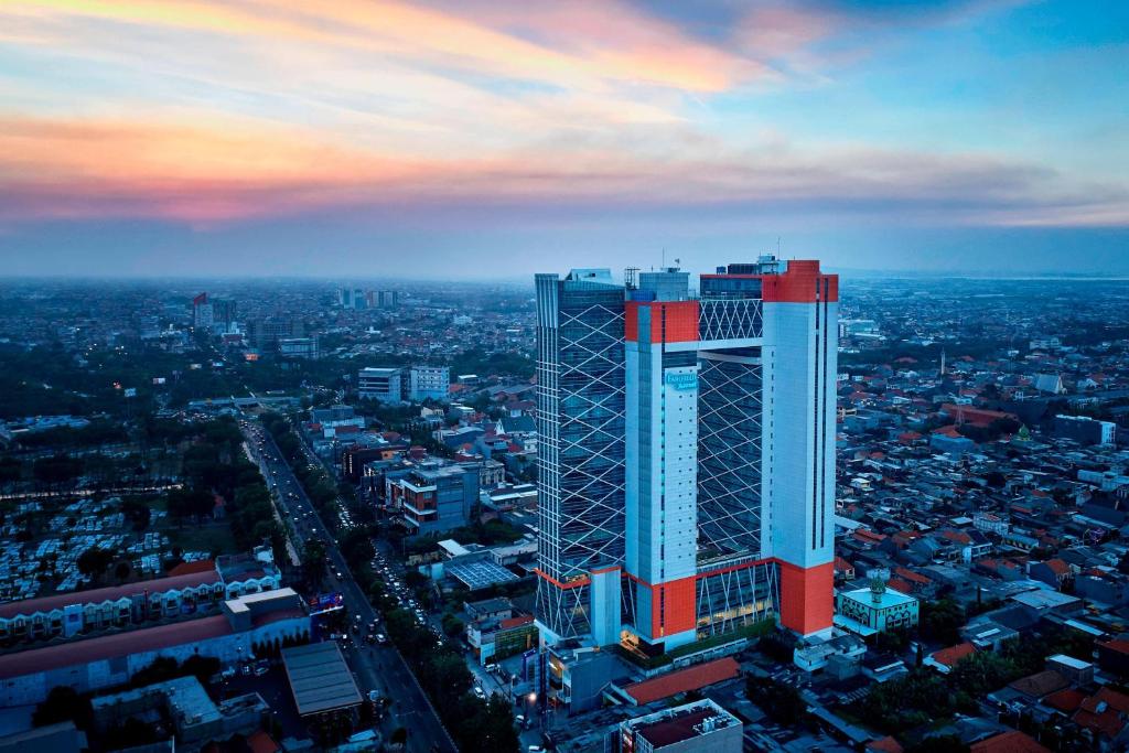a tall building with a red and white facade in a city at Fairfield by Marriott Surabaya in Surabaya