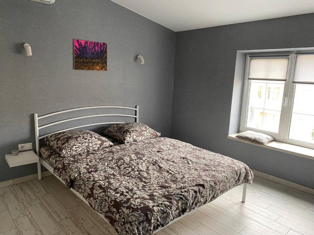 a bedroom with a bed with a comforter and two windows at GIL Apartments, Volodimirskaja 90.212 - Majetok Bozdosh in Uzhhorod