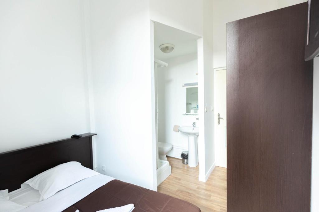 sypialnia z łóżkiem oraz łazienka z umywalką w obiekcie Hôtel Le Paris Brest w mieście Lens
