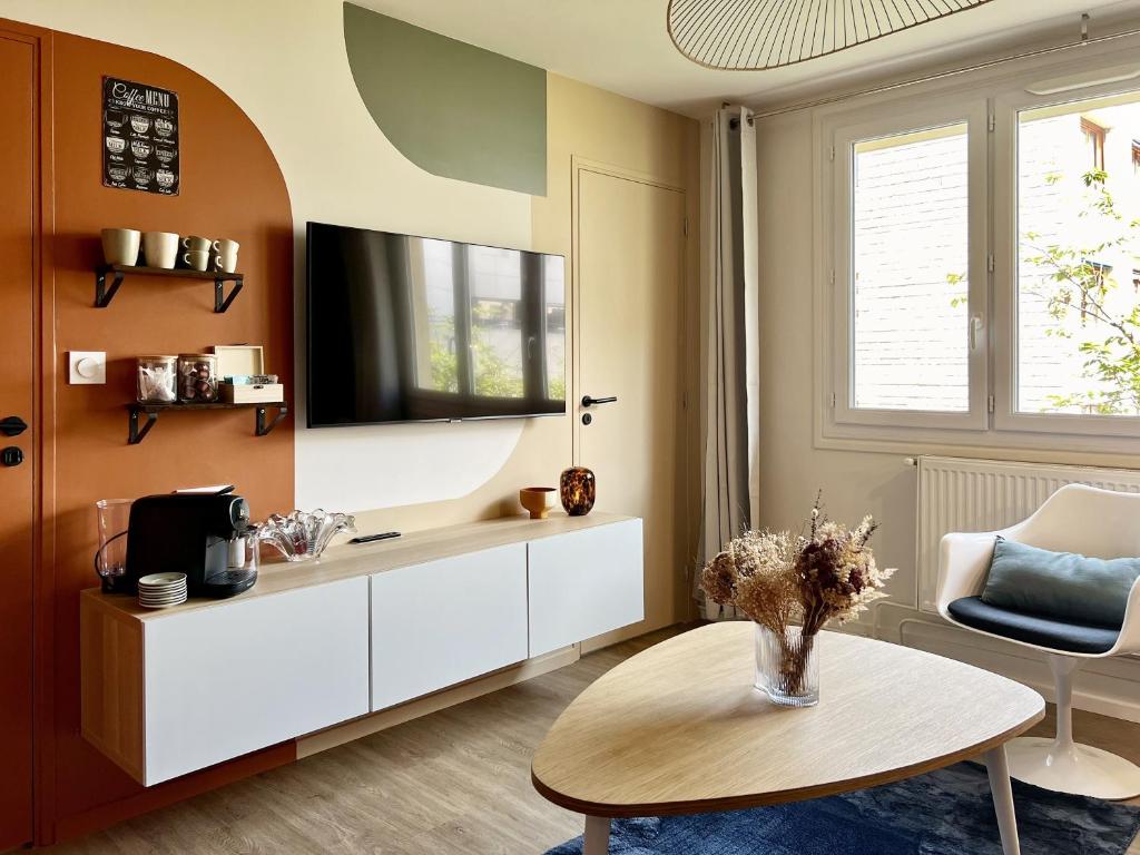 un salon avec une table et une télévision dans l'établissement L'Arc-en-Ciel Scandinave - Séjour unique et design au cœur de Rouen, à Rouen