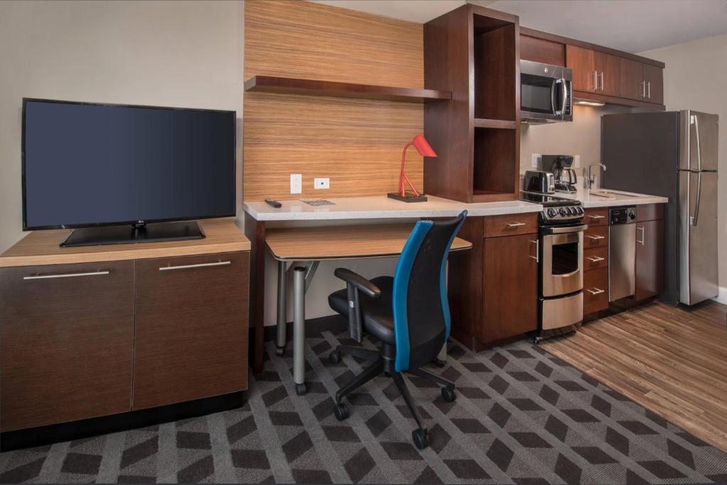 cocina con escritorio, TV y silla azul en TownePlace Suites by Marriott Altoona, en Altoona