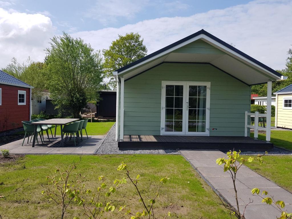 una pequeña casa verde con una mesa en un patio en De Bijsselse Enk, Noors chalet 15, en Nunspeet